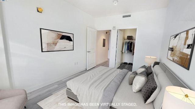 bedroom featuring a closet, light wood-type flooring, and a walk in closet