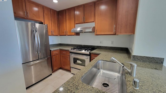 kitchen with stone counters, sink, light tile patterned floors, and stainless steel appliances