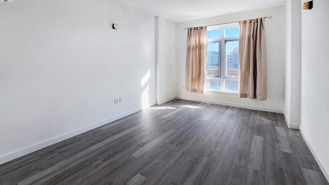 empty room with dark hardwood / wood-style flooring and a wealth of natural light