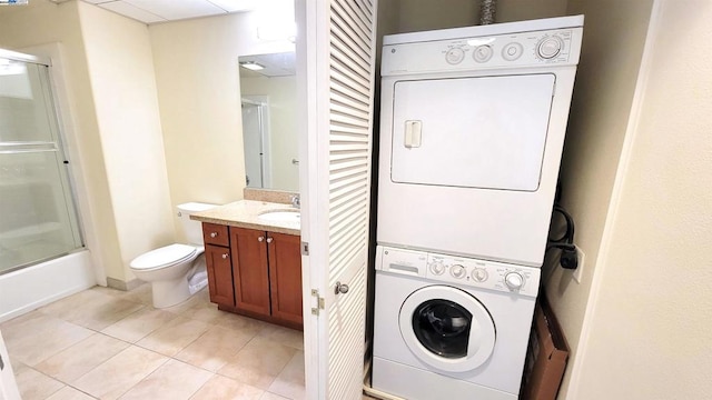 clothes washing area with light tile patterned flooring, sink, and stacked washing maching and dryer