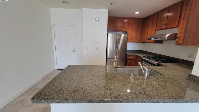 kitchen featuring sink, stainless steel appliances, stone counters, and kitchen peninsula