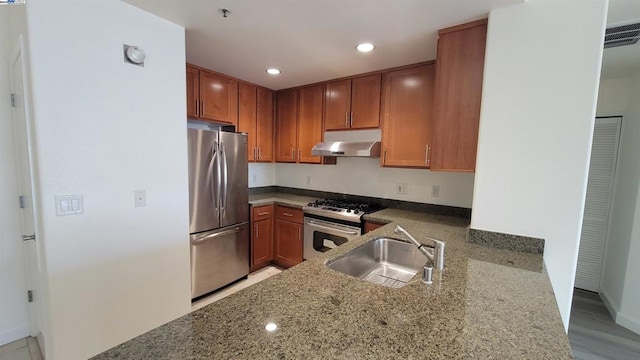 kitchen featuring light hardwood / wood-style floors, sink, kitchen peninsula, appliances with stainless steel finishes, and dark stone countertops