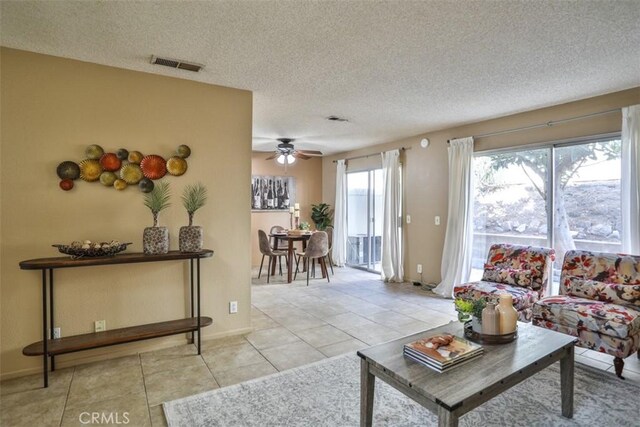 living room with light tile patterned floors, a textured ceiling, and ceiling fan