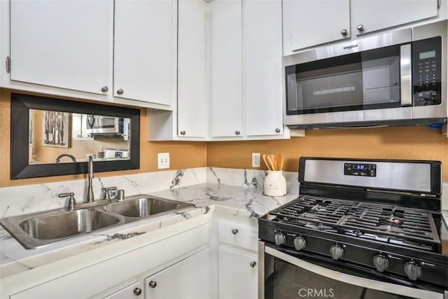 kitchen featuring appliances with stainless steel finishes, white cabinetry, and sink