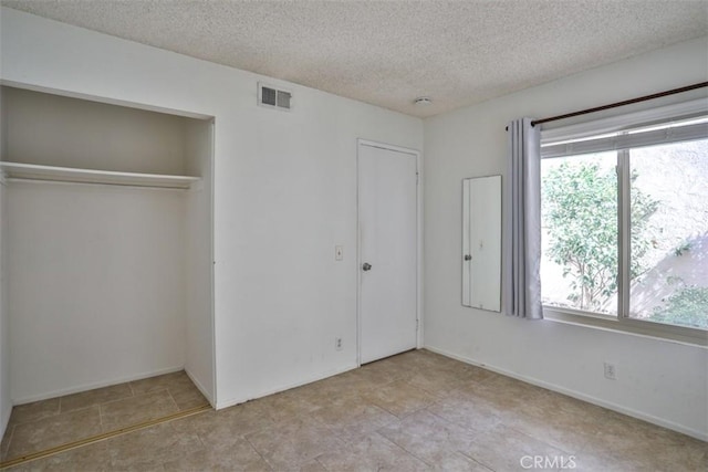 unfurnished bedroom with a closet, light tile patterned floors, and a textured ceiling