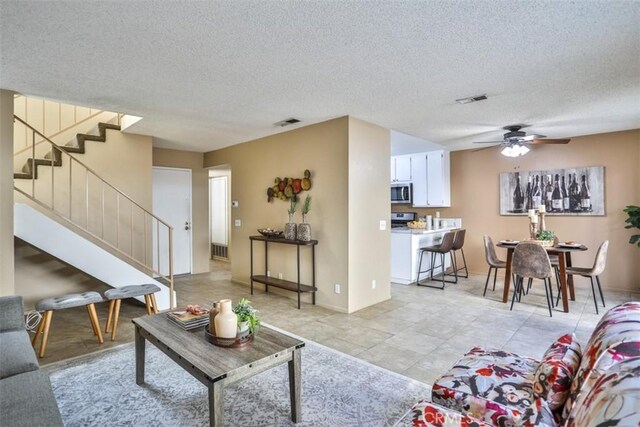 living room with a textured ceiling and ceiling fan