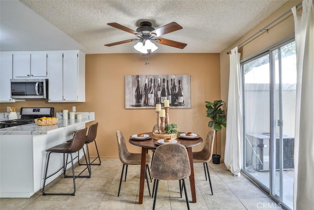 tiled dining area with ceiling fan and a textured ceiling