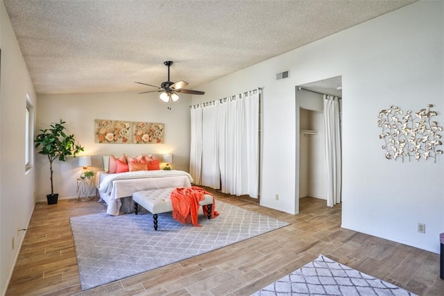 bedroom with ceiling fan, vaulted ceiling, a textured ceiling, and a closet