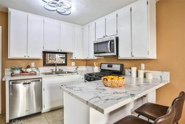 kitchen with stainless steel appliances, kitchen peninsula, and white cabinets