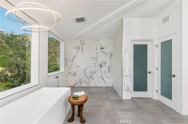 full bath with a chandelier, a freestanding tub, visible vents, and concrete flooring