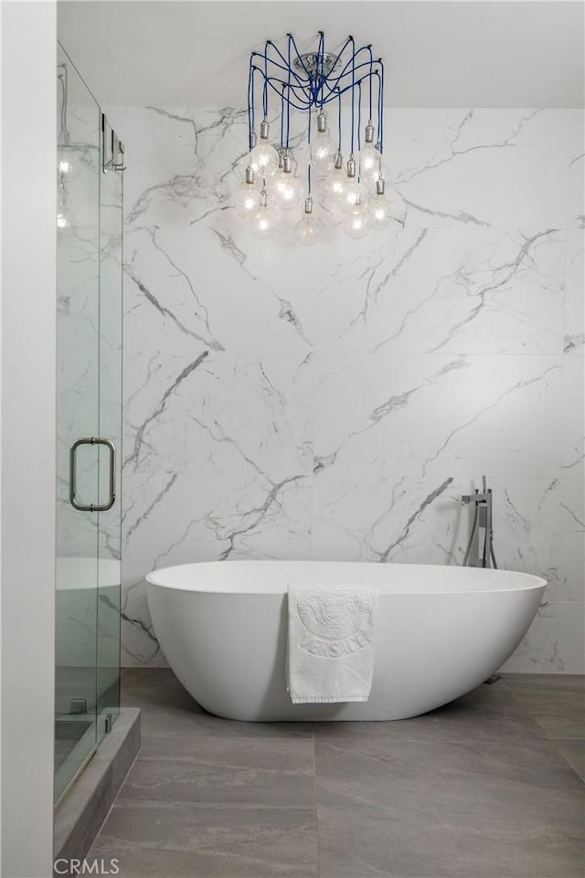 full bath with a freestanding bath, marble finish floor, a marble finish shower, and an inviting chandelier