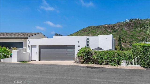 547 Temple Hills Dr, Laguna Beach, CA 92651 - contemporary home featuring an attached garage, stucco siding, a mountain view, and driveway