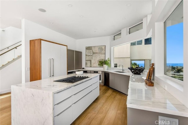 kitchen featuring light stone countertops, light wood finished floors, a sink, and modern cabinets