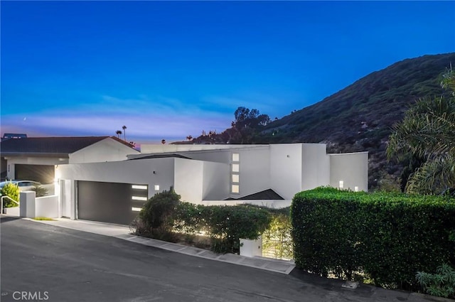 view of front of house with a garage, a mountain view, and stucco siding