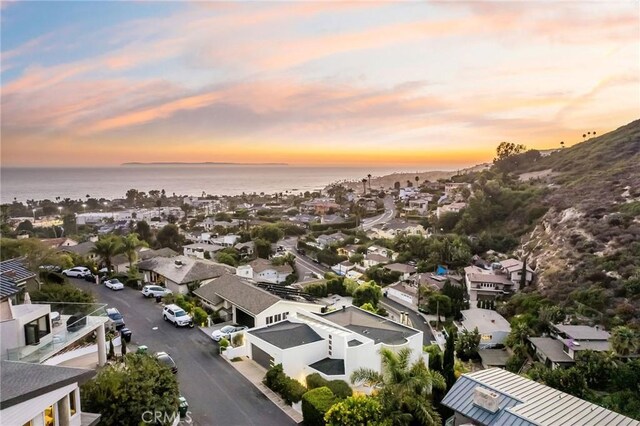 aerial view at dusk featuring a water view and a residential view