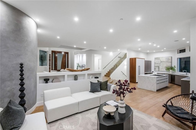 living area featuring recessed lighting, light wood-style floors, and stairway