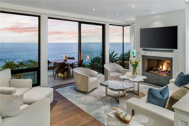 living room with a premium fireplace, a water view, and wood-type flooring