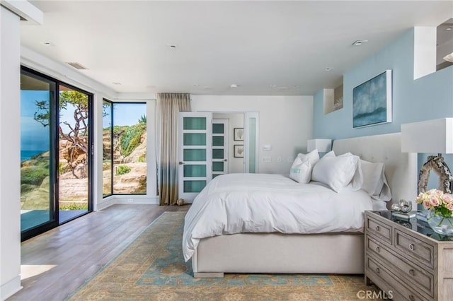 bedroom featuring access to exterior, visible vents, and wood finished floors