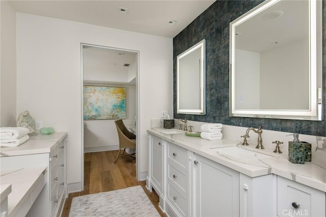 bathroom with double vanity, a sink, baseboards, and wood finished floors