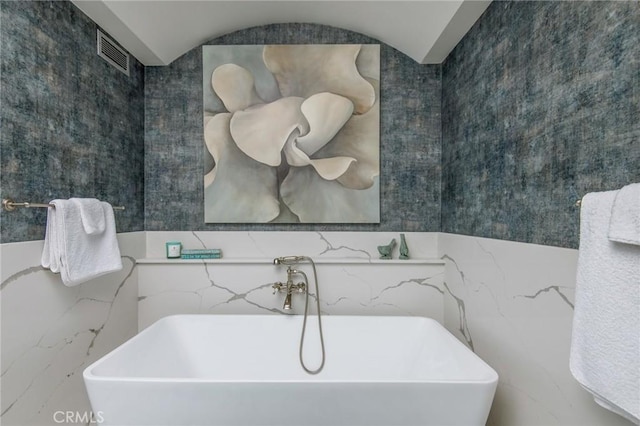 bathroom with a soaking tub, a sink, and visible vents