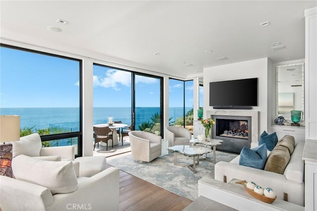 living room with expansive windows, a premium fireplace, and wood finished floors