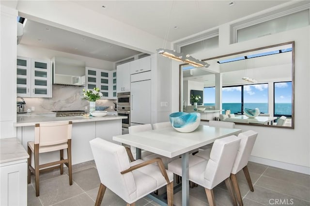 dining area featuring light tile patterned floors and a water view