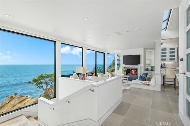 living room featuring light tile patterned floors, a wall of windows, and a water view