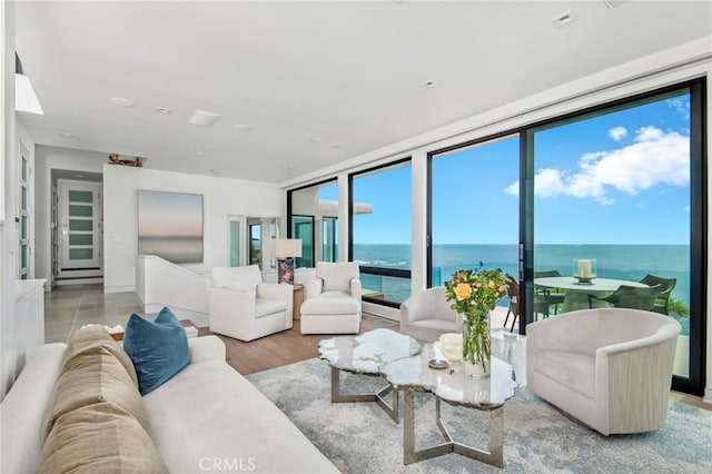 living area featuring a water view, a wall of windows, and wood finished floors