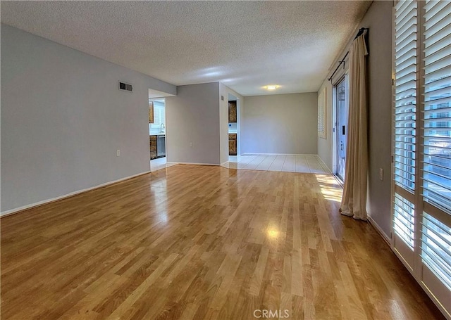 unfurnished room with light hardwood / wood-style floors and a textured ceiling