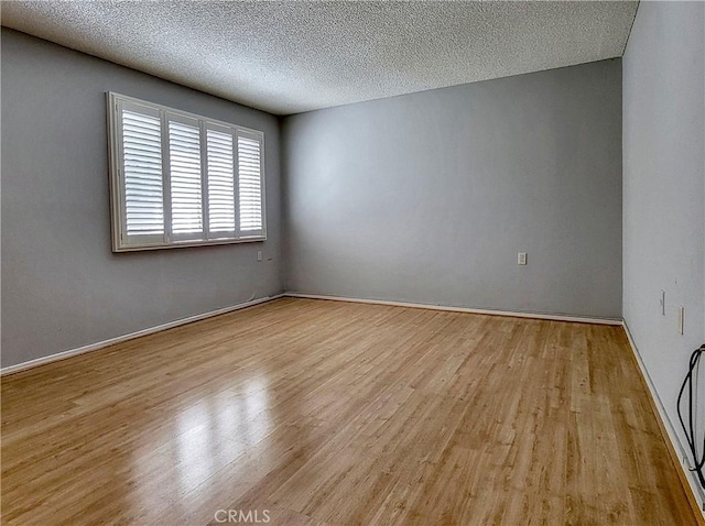 spare room with a textured ceiling and light hardwood / wood-style flooring