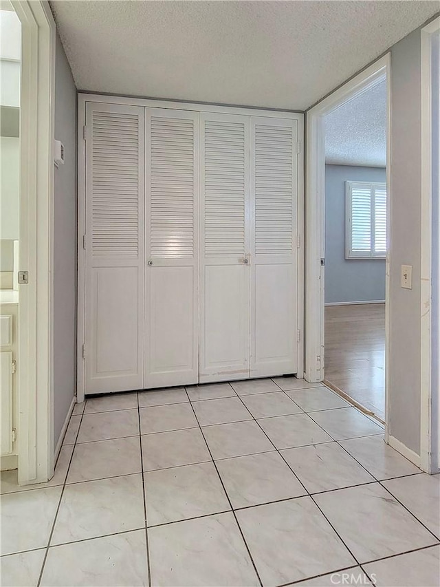 unfurnished bedroom with a closet, light tile patterned floors, and a textured ceiling