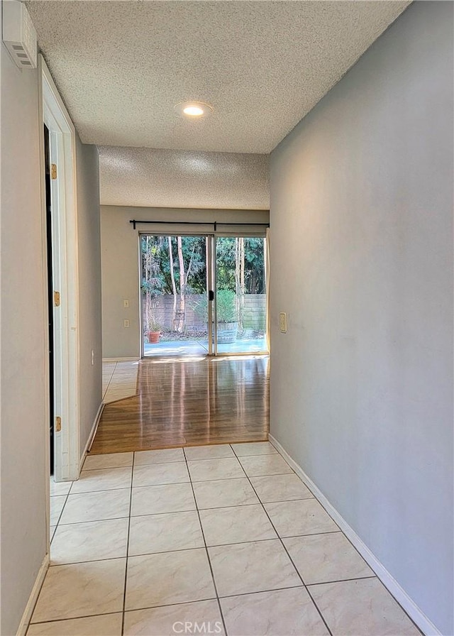 hallway featuring light hardwood / wood-style floors and a textured ceiling