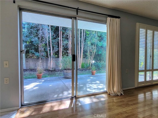 doorway to outside with hardwood / wood-style floors, a textured ceiling, and a wealth of natural light