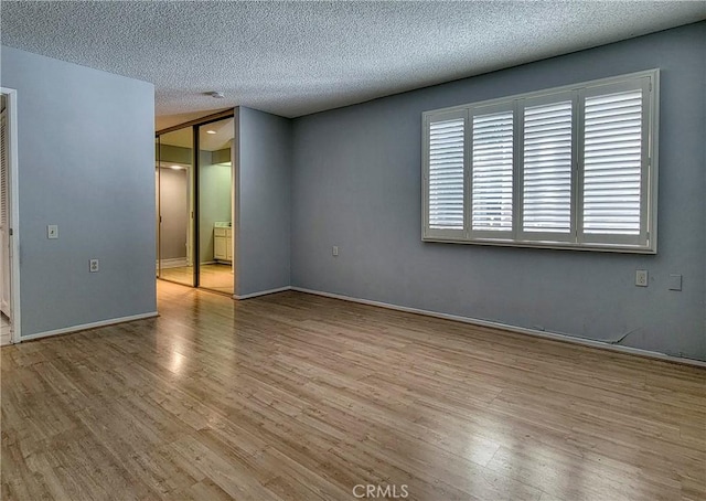 unfurnished room with a textured ceiling and light wood-type flooring