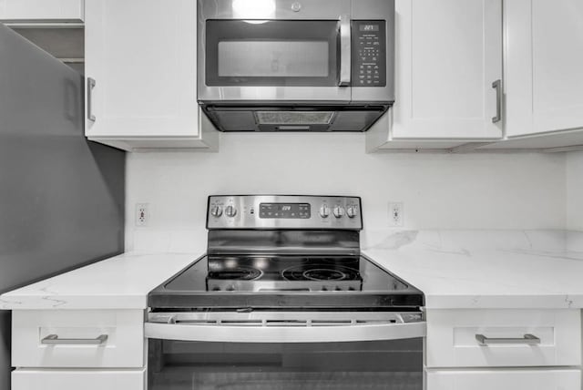 kitchen featuring ventilation hood, light stone countertops, stainless steel appliances, and white cabinetry