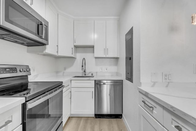 kitchen featuring light wood-type flooring, sink, stainless steel appliances, and white cabinetry