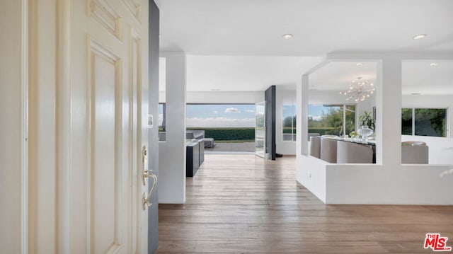 corridor featuring an inviting chandelier and hardwood / wood-style flooring