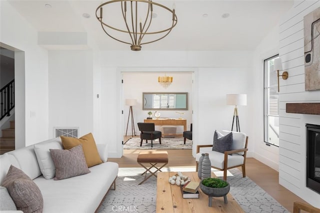 living room featuring a fireplace, wood-type flooring, and a notable chandelier