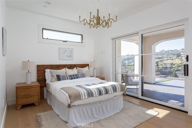 bedroom with hardwood / wood-style flooring, access to exterior, and an inviting chandelier