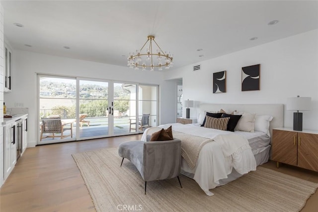 bedroom featuring access to exterior, light hardwood / wood-style flooring, a chandelier, and french doors