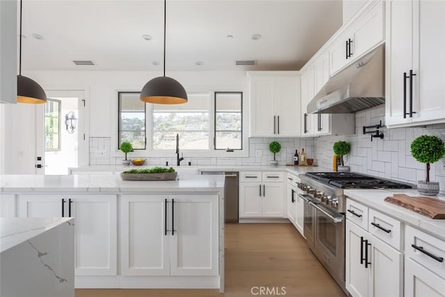 kitchen featuring light stone counters, white cabinets, pendant lighting, and appliances with stainless steel finishes