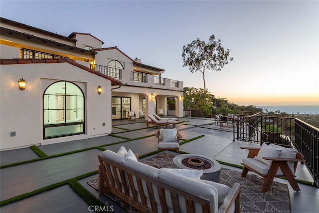 patio terrace at dusk with a balcony and an outdoor living space with a fire pit