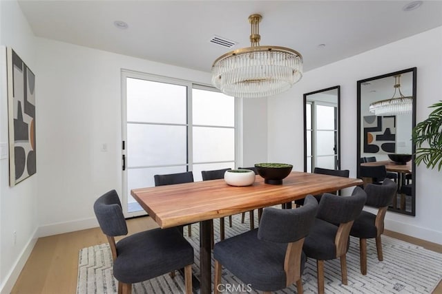 dining area with a chandelier and light hardwood / wood-style flooring