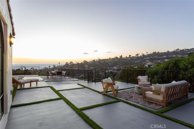 patio terrace at dusk with a water view and an outdoor living space with a fire pit