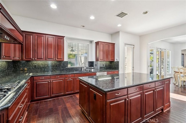 kitchen with sink, a kitchen island, a healthy amount of sunlight, and dark hardwood / wood-style floors