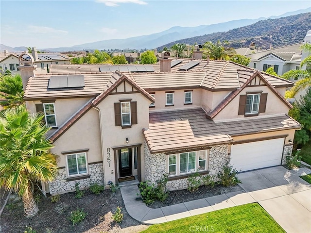 view of front of home featuring a mountain view, a garage, and solar panels