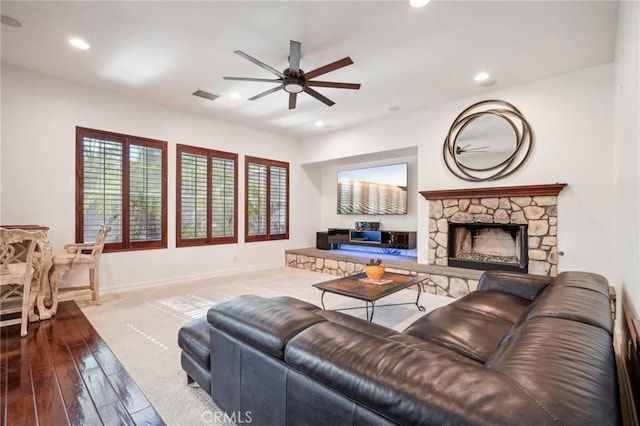 living room featuring hardwood / wood-style floors, a stone fireplace, and ceiling fan