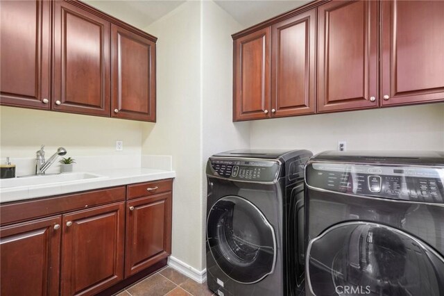 clothes washing area with cabinets, washing machine and dryer, dark tile patterned flooring, and sink