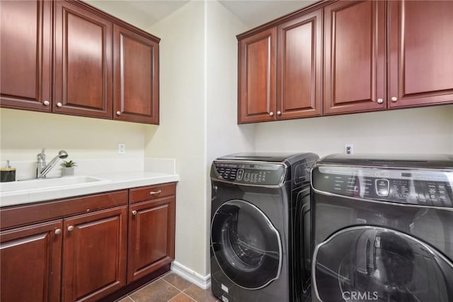 laundry area featuring sink, washer and clothes dryer, cabinets, and dark tile patterned floors