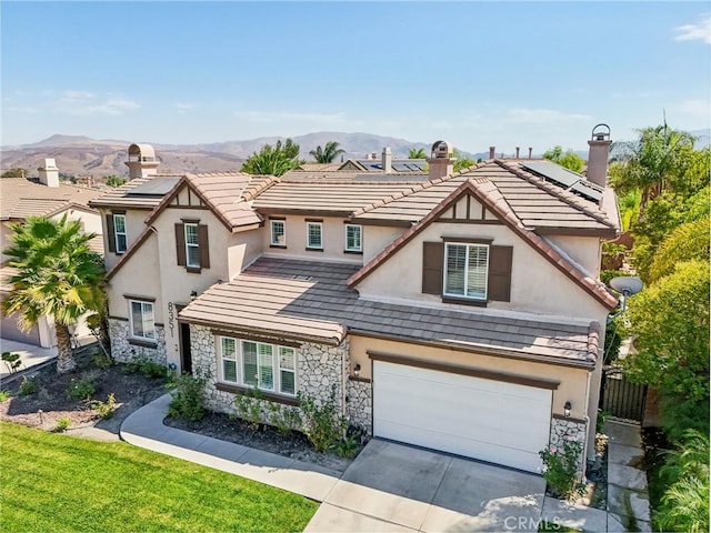 view of front of home featuring a garage, a mountain view, a front lawn, and solar panels